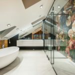 L’Aménagement de Combles : Guide Complet pour Transformer son Espace Perdu L'Aménagement de Combles : Guide Complet pour Transformer son Espace Perdu L'aménagement des combles représente une solution privilégiée pour augmenter significativement la surface habitable d'une maison sans avoir recours à une coûteuse extension latérale ou à une construction neuve. C'est un projet de rénovation qui, bien planifié et exécuté, apporte une réelle plus-value au bien immobilier. Cependant, transformer un grenier sombre et inutilisé en pièces de vie lumineuses et confortables (chambres, bureau, salle de bain) est un chantier complexe qui soulève de nombreuses questions techniques, réglementaires et financières. Ce guide détaillé de plus de 1000 mots explore les étapes cruciales, des vérifications initiales à la réception des travaux, en insistant sur les aspects essentiels que sont la structure, l'isolation et la lumière naturelle. I. Diagnostic Initial : Faisabilité Technique et Réglementaire Avant même de penser au design intérieur, il est indispensable de valider la faisabilité du projet sur deux plans fondamentaux : la structure du bâti et les exigences urbanistiques. II. La Vérification de la Structure de la Charpente Le principal obstacle technique à l'aménagement est souvent la configuration de la charpente. On distingue principalement deux types de charpentes : Les Charpentes Traditionnelles : Caractérisées par des poutres espacées et peu d'entraves au centre. Elles offrent généralement un volume suffisant pour un aménagement sans modification majeure de la structure portante. Les Charpentes Industrielles ou Fermettes : Fréquemment utilisées dans les constructions modernes, elles sont composées de nombreux bois de faible section formant des W ou des M, qui occupent l'espace central. Elles nécessitent une modification structurelle importante, souvent appelée "modification de charpente" ou "charpente en A", pour libérer l'espace. Cette opération est délicate et doit être réalisée par des entreprises spécialisées, car elle implique de reporter les charges du toit sur les murs porteurs via des renforts (poutres ou portiques métalliques). Il faut également s'assurer que le plancher existant est capable de supporter une charge d'habitation (environ 150 kg/m²). Dans le cas contraire, un renforcement du plancher, voire la création d'un nouveau plancher porteur, est nécessaire, souvent réalisé à l'aide de poutres en bois lamellé-collé ou de solives supplémentaires. III. Les Critères de Faisabilité et les Hauteurs Sous Plafond L'espace n'est considéré comme aménageable qu'à partir d'une certaine hauteur. La règle d'or est d'avoir au moins 1,80 mètre de hauteur sous plafond sur une surface significative au centre de la pièce pour pouvoir y circuler confortablement. Une pente de toit (ou rampant) supérieure à 30 degrés est souvent idéale pour atteindre cette hauteur. Si la hauteur est insuffisante, deux solutions lourdes peuvent être envisagées : La Modification de la Pente : Travaux lourds consistant à surélever la toiture pour augmenter la hauteur sous faîtage. Le Décaissement : Abaisser le plancher de l'étage inférieur, ce qui est très invasif et coûteux. IV. Les Formalités Administratives et Permis de Construire Le projet d'aménagement est soumis à la réglementation d'urbanisme locale (Plan Local d'Urbanisme - PLU). Le type d'autorisation dépend de la surface créée et de la modification de l'aspect extérieur : Déclaration Préalable de Travaux (DP) : Nécessaire si la surface de plancher créée est inférieure à 20 m² (ou 40 m² en zone urbaine couverte par un PLU) et si le projet implique la création d'ouvertures (fenêtres de toit ou lucarnes). Permis de Construire (PC) : Obligatoire si la surface de plancher totale créée dépasse 40 m² ou si la surface totale de la maison (après travaux) dépasse les 150 m², nécessitant alors le recours à un architecte. Le non-respect de ces règles expose le propriétaire à des sanctions (amende, obligation de démolition). Il est impératif de consulter la mairie en amont du lancement des travaux. V. L'Isolation Thermique et Phonique : Un Enjeu Majeur L'isolation est sans doute l'étape la plus critique pour garantir le confort et la performance énergétique des combles. Le toit est la principale source de déperdition thermique (jusqu'à 30 % de la chaleur totale de la maison). 1. L'Isolation des Rampants L'isolation est généralement réalisée par l'intérieur, directement sous la toiture, entre ou sous les chevrons. Il est essentiel d'atteindre une résistance thermique (R) élevée, souvent supérieure à 6 ou 7 m².K/W, pour respecter les normes environnementales actuelles (notamment la réglementation thermique ou environnementale en vigueur, comme la RE2020 pour les constructions neuves, bien que les combles rénovés soient soumis à la réglementation RGE). Les matériaux couramment utilisés incluent la laine de verre, la laine de roche, la fibre de bois ou le polyuréthane. 2. La Gestion de la Vapeur et l'Étanchéité L'installation d'un pare-vapeur ou d'un frein-vapeur est cruciale pour éviter que l'humidité intérieure ne migre vers l'isolant et la charpente, ce qui pourrait provoquer la condensation, la perte d'efficacité de l'isolant et la dégradation du bois (moisissures). Une lame d'air ventilée entre l'isolant et la couverture extérieure est souvent indispensable pour la bonne respiration du toit. 3. L'Isolation Phonique Comme les combles sont directement sous le toit, l'isolation phonique contre les bruits d'impact (pluie, grêle) et les bruits aériens est très importante. L'utilisation d'isolants denses (laine de roche, fibre de bois) ou l'ajout de plaques de plâtre à haute densité améliore considérablement le confort acoustique. VI. L'Apport de Lumière Naturelle et l'Aération Un aménagement réussi est un aménagement lumineux. L'apport de lumière naturelle est non seulement essentiel pour le confort visuel, mais il permet également de réduire la dépendance à l'éclairage artificiel. 1. Les Fenêtres de Toit (Velux) Les fenêtres de toit sont la solution la plus courante. Elles sont installées parallèlement au rampant. Leur taille et leur nombre doivent être calculés pour que la surface vitrée représente au moins 1/6e de la surface habitable de la pièce. Leur positionnement est stratégique : elles doivent être accessibles pour l'ouverture et suffisamment hautes pour ne pas être gênées par le mobilier. Elles contribuent également activement à la ventilation. 2. Les Lucarnes et Chien-Assis La création de lucarnes ou de chien-assis est un travail de maçonnerie plus complexe. Ces structures modifient l'aspect extérieur de la toiture mais offrent l'avantage d'une hauteur d'ouverture verticale et permettent de gagner de la surface utilisable près des murs. 3. La Ventilation Une bonne aération est vitale pour la qualité de l'air et la régulation de l'humidité. Si l'aménagement crée des pièces humides (salle de bain), l'installation d'une ventilation mécanique contrôlée (VMC) est obligatoire pour évacuer l'humidité. Même pour les chambres ou bureaux, une ventilation naturelle par les fenêtres est nécessaire, complétée idéalement par un système VMC double flux. VII. Les Aménagements Intérieurs et les Finitions L'aménagement intérieur doit optimiser l'espace sous les pentes, souvent exigu. 1. Les Cloisons et la Distribution des Pièces Les cloisons légères (plaques de plâtre) sont privilégiées pour ne pas surcharger la structure du plancher. L'agencement doit tenir compte de la hauteur libre, en plaçant les zones nécessitant de se tenir debout (douche, bureau, tête de lit) sous les points les plus hauts. 2. L'Électricité et la Plomberie Tous les réseaux (électricité, plomberie, chauffage) doivent être tirés depuis l'étage inférieur. L'électricité doit respecter les normes de sécurité en vigueur (norme NF C 15-100). Pour la plomberie, il est judicieux de positionner les pièces d'eau (salle de bain, toilettes) à l'aplomb des évacuations existantes pour simplifier le raccordement et minimiser les coûts. L'installation d'un ballon d'eau chaude supplémentaire peut être envisagée si le réseau existant est insuffisant. 3. Les Accès et l'Escalier La création d'un accès permanent est essentielle. L'escalier doit être sécurisé et ne pas empiéter excessivement sur l'espace de l'étage inférieur. Le choix du type d'escalier (droit, en colimaçon, quart-tournant) dépend de la trémie disponible et de la fréquence d'utilisation des combles. Un escalier bien conçu est à la fois fonctionnel et un élément esthétique de l'habitation. VIII. Conclusion : Planification et Valorisation L'aménagement de combles est un investissement conséquent, mais son retour est double : un gain substantiel en qualité de vie grâce à de nouvelles pièces, et une augmentation significative de la valeur immobilière. Le coût global d'un tel projet varie fortement (entre 800 et 1 500 euros par mètre carré) en fonction de la complexité de la charpente à modifier et de la qualité des finitions choisies. Une planification rigoureuse, l'intervention d'un bureau d'études structure (si la charpente est modifiée) et le recours à des artisans qualifiés (idéalement RGE pour les aides financières liées à l'isolation) sont les garants d'un projet mené à bien. Ne négliger aucune étape, notamment les études de faisabilité et l'isolation, est la clé pour transformer l'espace sous votre toit en un véritable lieu de vie agréable et pérenne.